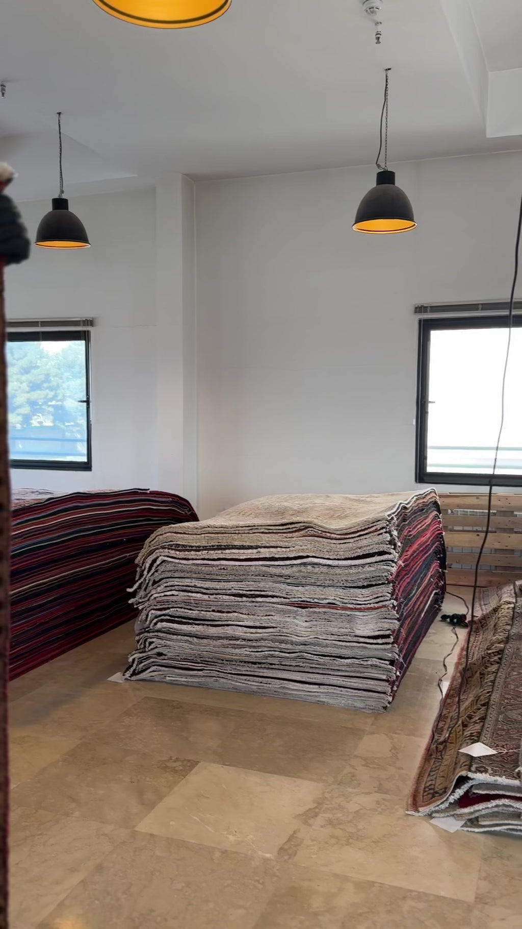 Interior view of a rug showroom with stacked rugs in neutral tones, providing context for the Hand-Knotted Vintage Wool Area Rug – 7' x 3' 9".