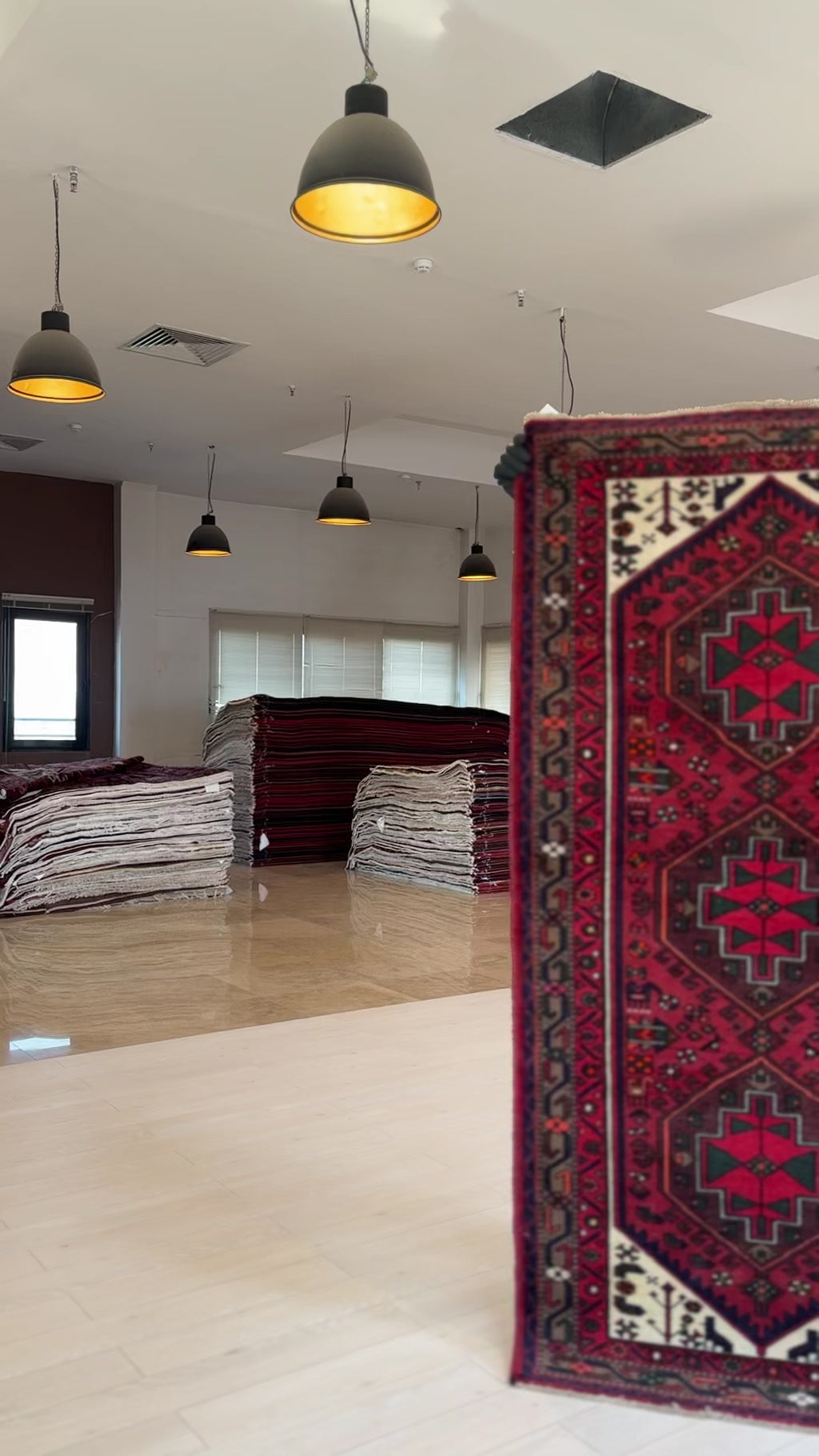 Close-up side view of Hand-Knotted Vintage Wool Area Rug – 6' 8" x 3' 4" in a showroom with stacked rugs in the background.