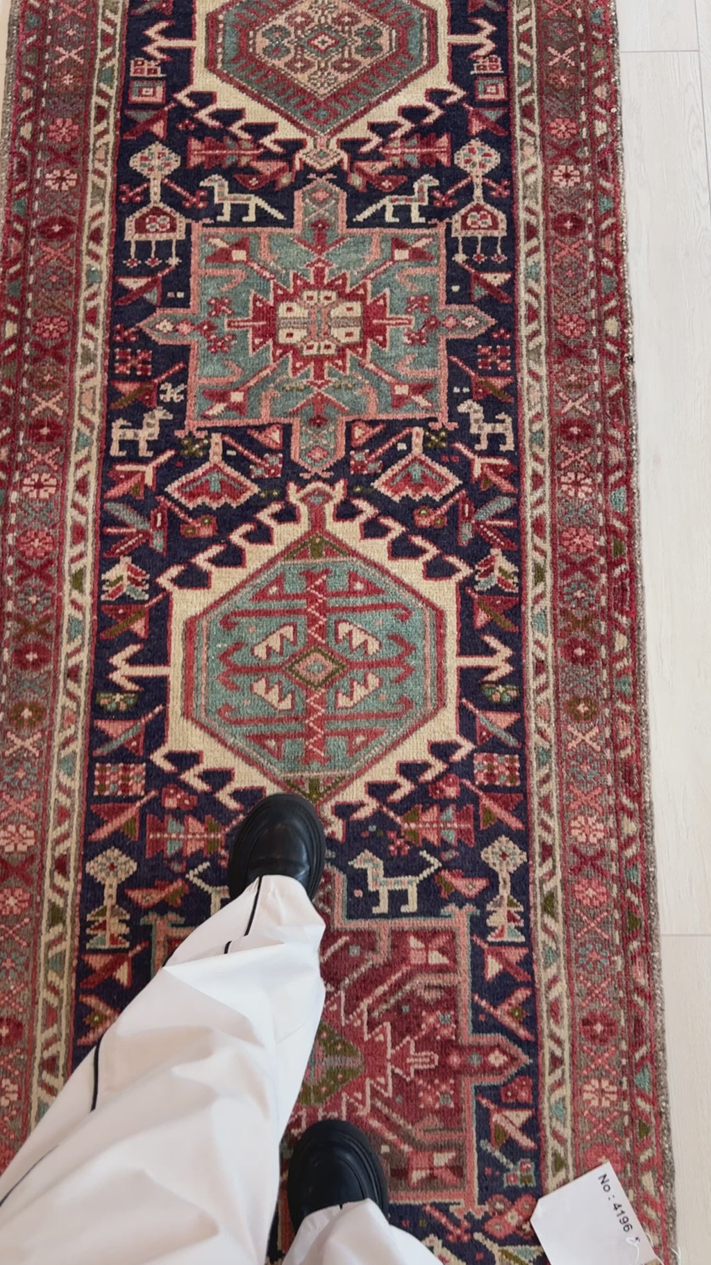 Detailed view of vintage wool runner rug 10' 9" x 2' 10" with tribal medallions and person standing on it for size reference.