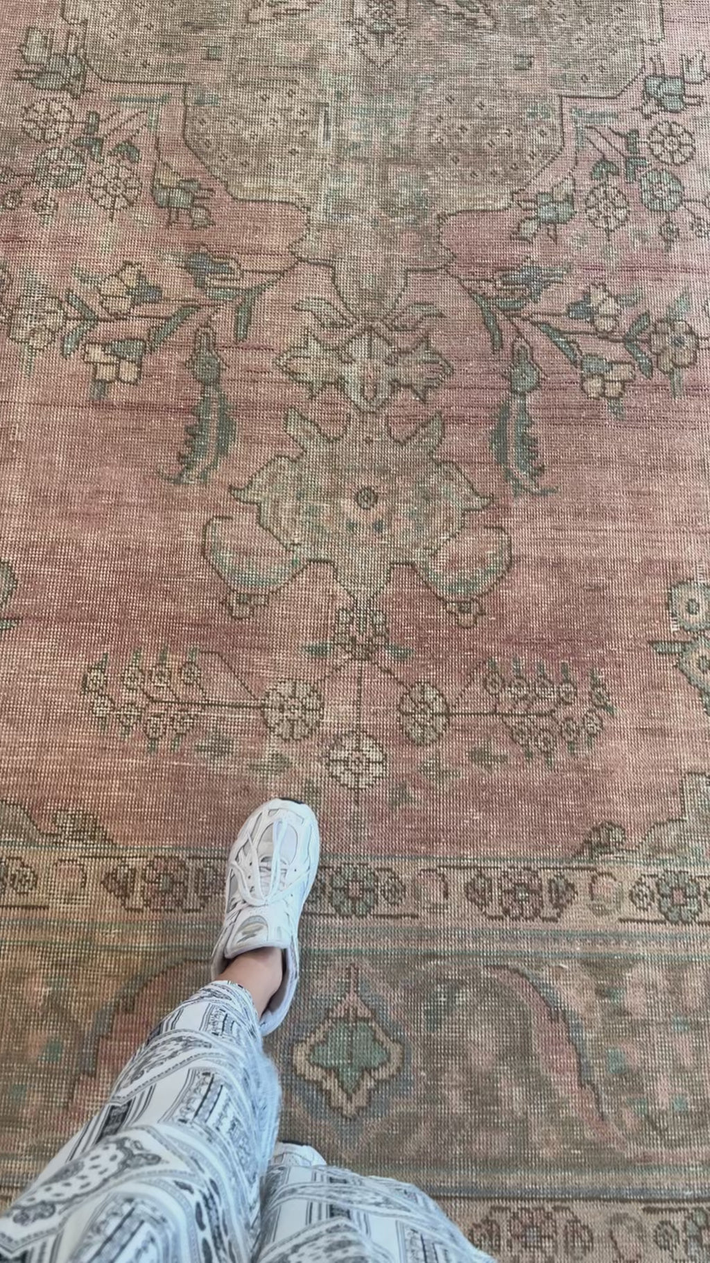 Close-up of hand-knotted antique neutral faded pink Persian 9x12 rug showing detailed floral patterns and soft wool texture underfoot.