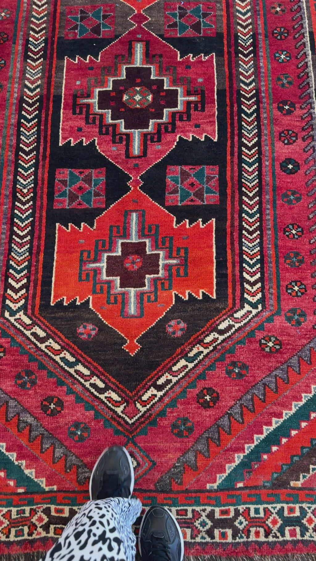 Close-up of Hand-Knotted Vintage Wool Area Rug – 9' x 5' showing intricate tribal motifs and rich red and black color palette underfoot.