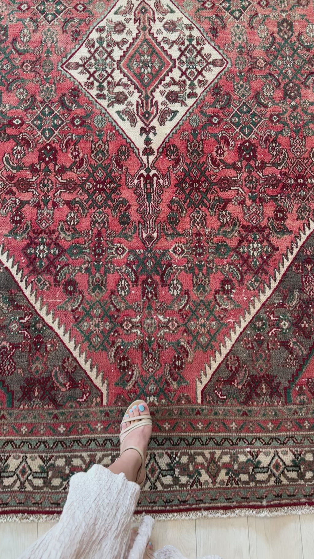 Detailed view of Hand-Knotted Vintage Large Wool Area Rug – 9' 9" x 6' 4" highlighting rich red tones and symmetrical medallion with foot for scale.