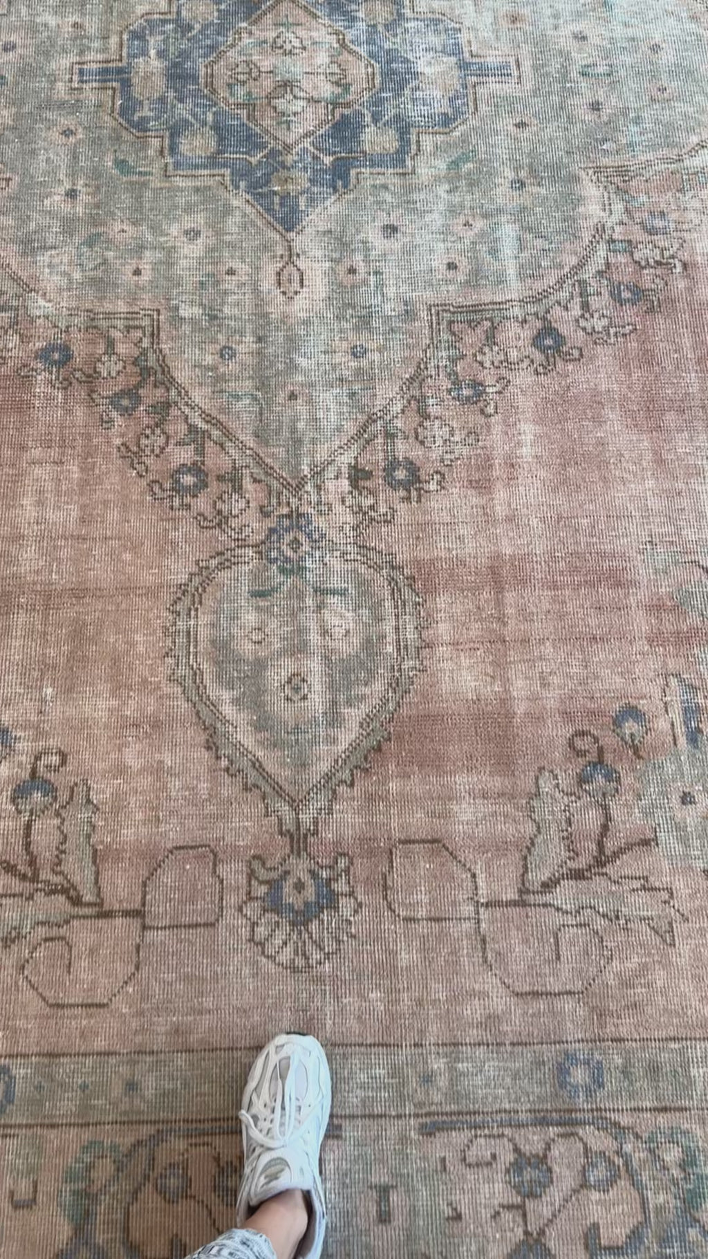Close-up of hand-knotted Tabriz vintage wool rug showing intricate faded floral patterns and texture underfoot.
