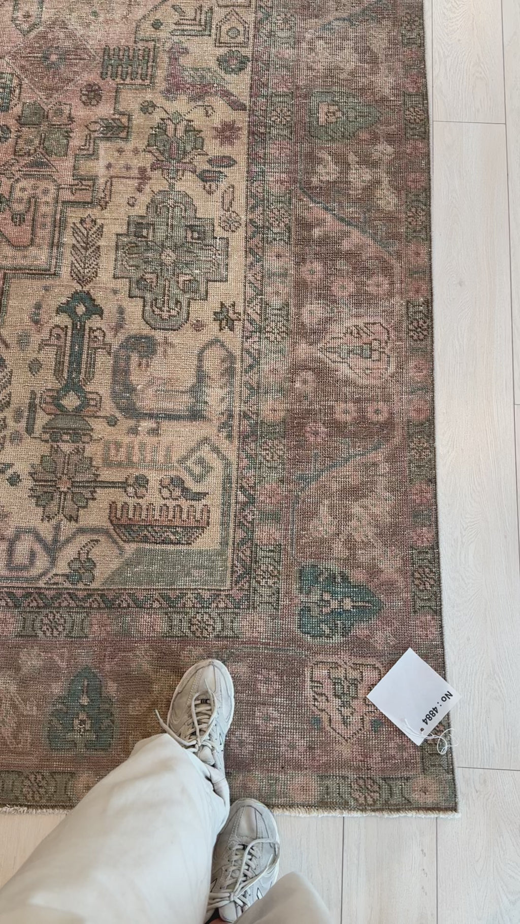 Close-up of corner detail on hand-knotted vintage wool rug, 12'7" x 9'1", highlighting faded tribal motifs and soft pastel colors.