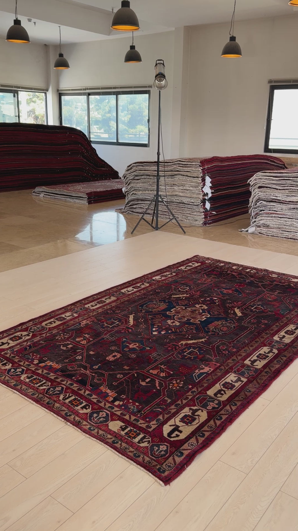 Hand-Knotted Vintage Wool Area Rug – 10' 2" x 6' displayed in a showroom with stacked rugs, highlighting its authentic craftsmanship and size.